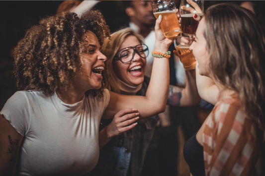 Frauen feiern und stoßen mit Alkohol Drinks an