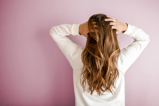 Eine Frau mit langen Haaren fasst sich in die Haare