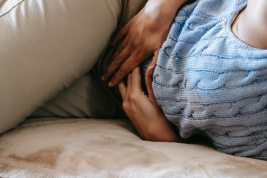 Eine Frau mit Bauchschmerzen liegt auf der Seite und hält sich den Bauch