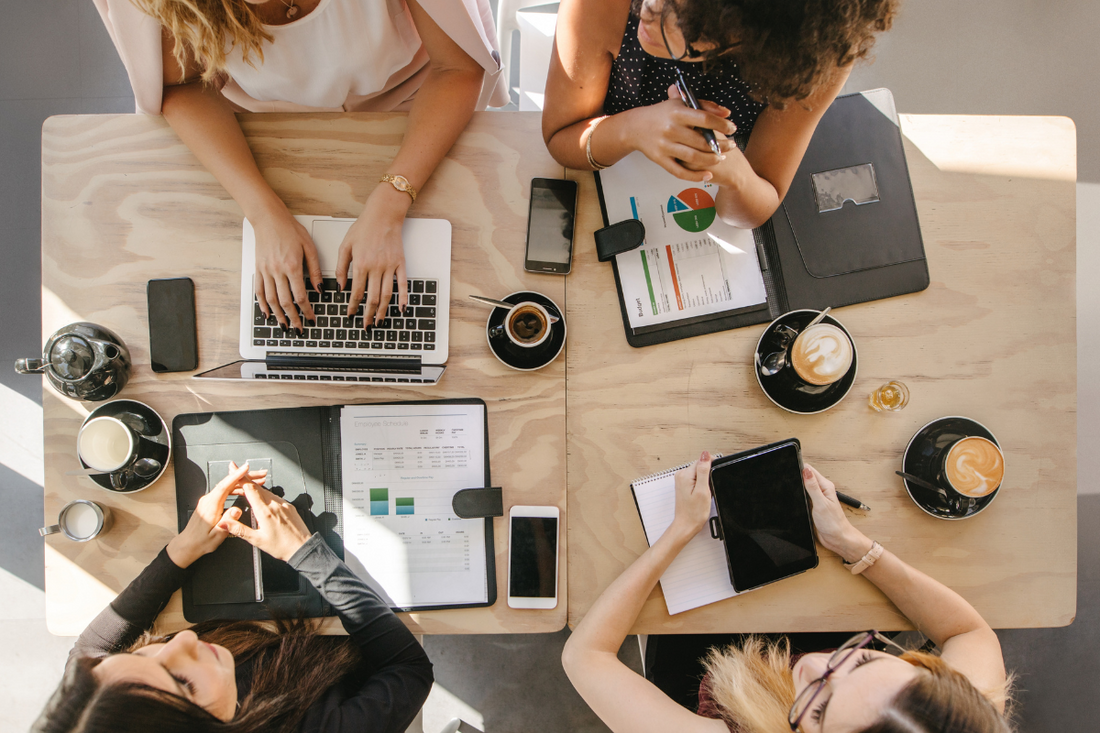 Mehrere Frauen sitzen an einem Tisch und arbeiten, coworken