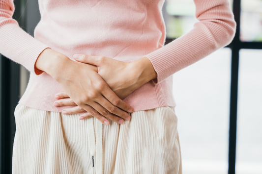 Eine Frau mit Regelschmerzen hält ihre Hände über Ihren Bauch