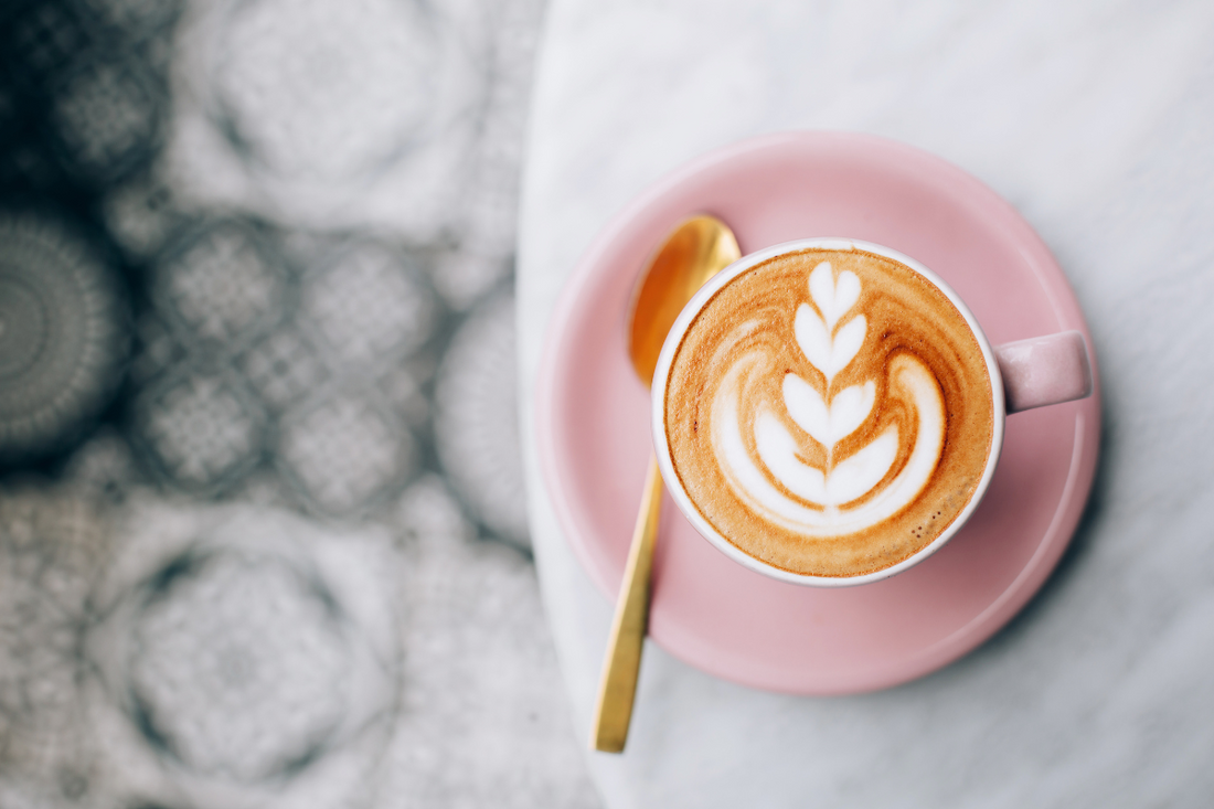 Eine Tasse Kaffee mit schöner Barista Verzierung steht auf einem Tisch