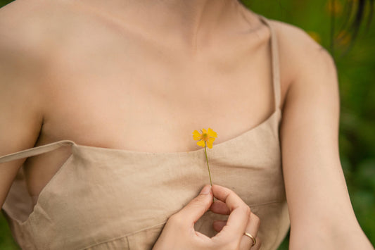 Eine Frau hält eine gelbe Blume vor ihre Brust